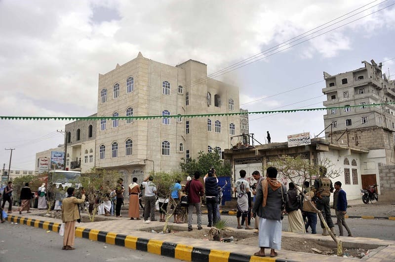Crowds watch as smokes billows out from a building